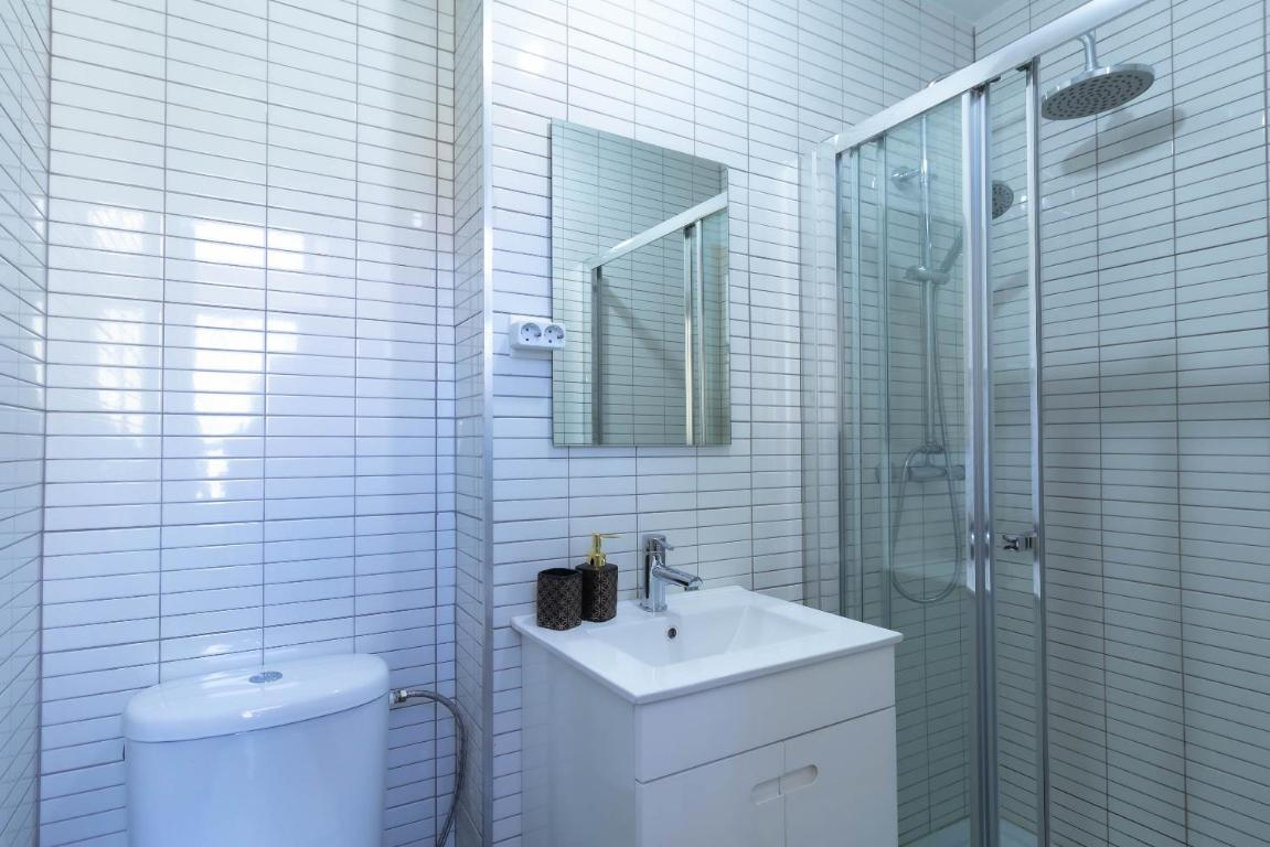 um banheiro com azulejos brancos e uma pia branca