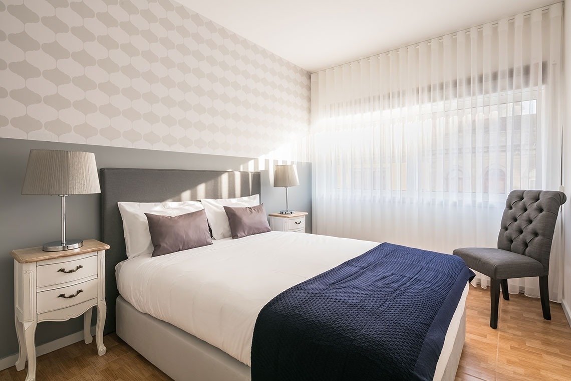 um quarto com uma cama , duas mesas de cabeceira e uma cadeira