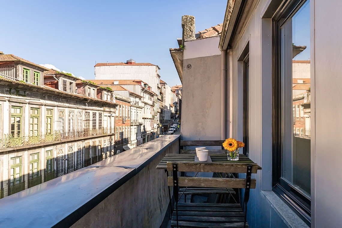 uma varanda com uma mesa de madeira e um vaso de flores