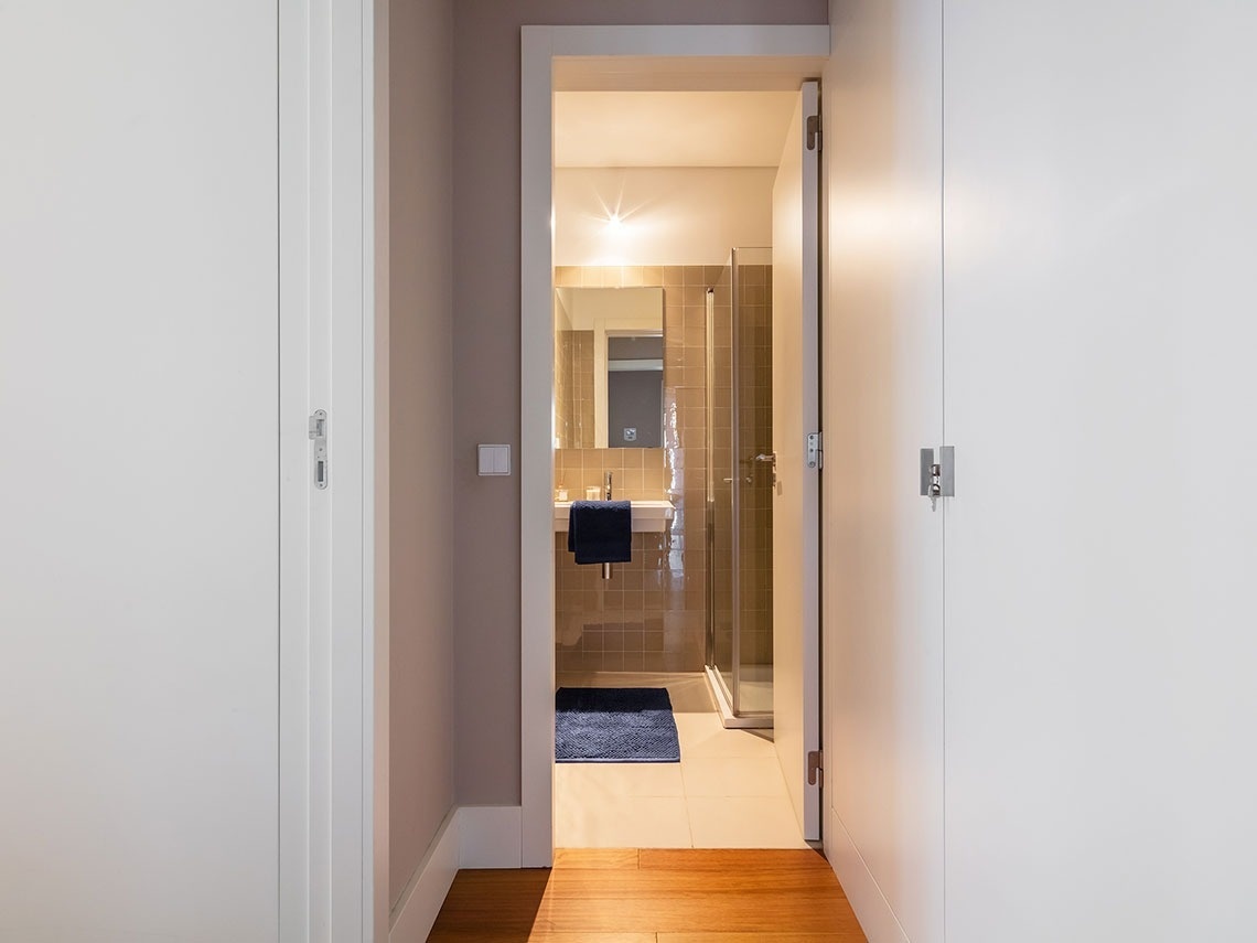 uma porta branca leva a um banheiro com pia e chuveiro