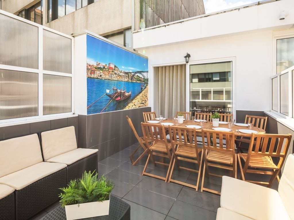 uma mesa e cadeiras em uma varanda com uma pintura de um barco no fundo