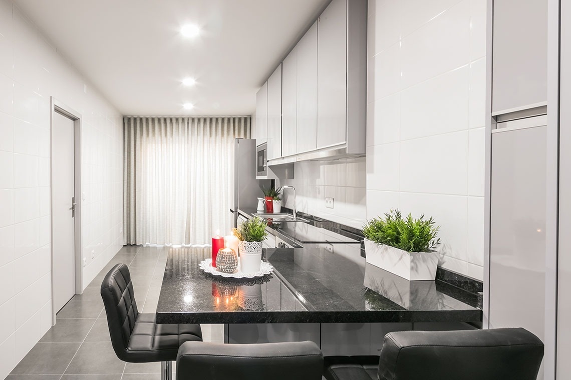 uma cozinha branca e preta com velas e vasos de plantas