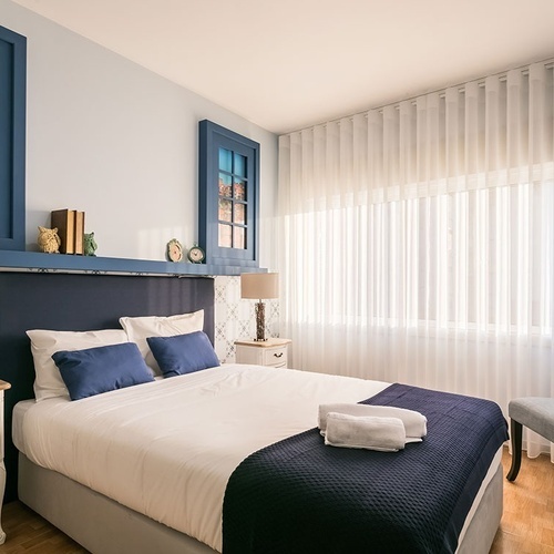 a bedroom with a blue headboard and white curtains