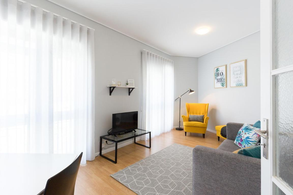 uma sala de estar com um sofá cinza e uma cadeira amarela