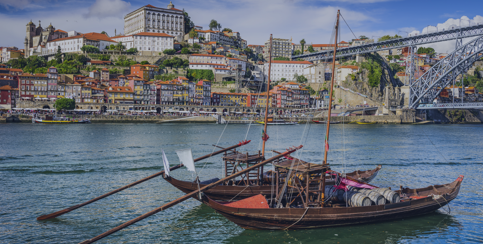 dois barcos estão ancorados na água com uma ponte ao fundo