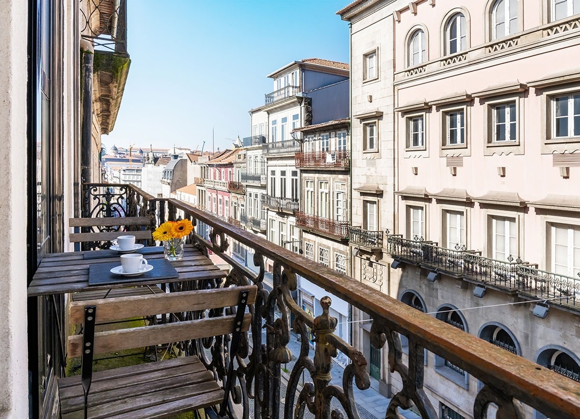 uma varanda com uma mesa de madeira e duas xícaras de café