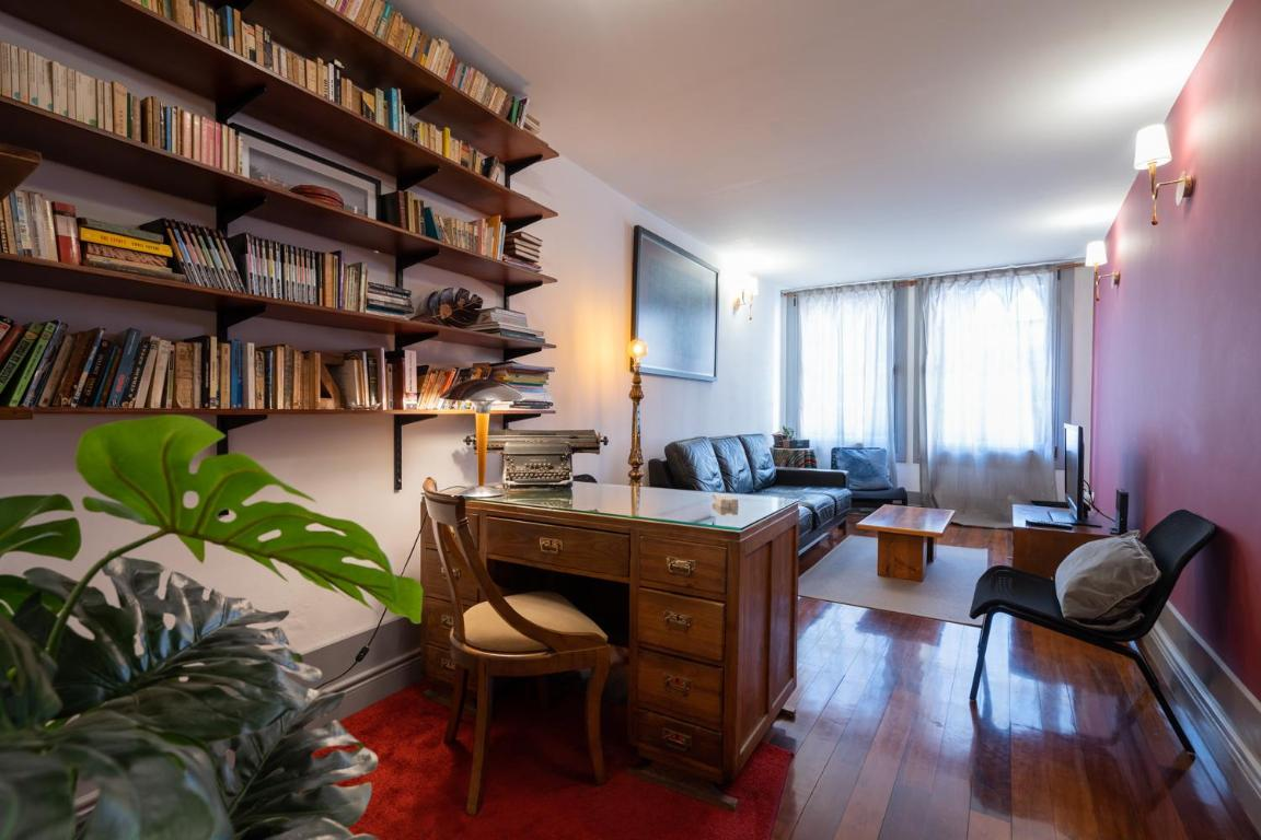 uma sala de estar com um sofá e uma mesa e prateleiras cheias de livros