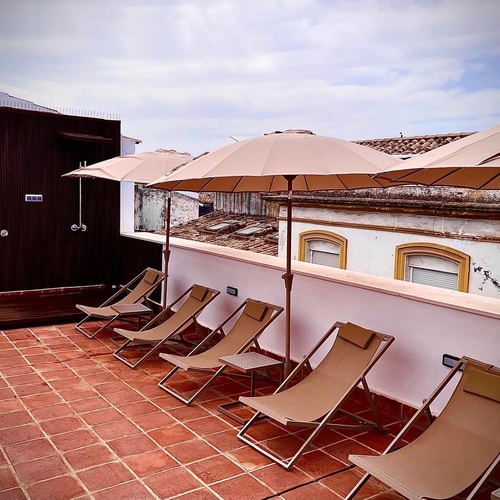 sillas y sombrillas en una terraza con una ducha en el fondo