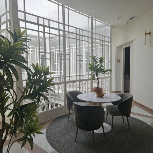 una sala de estar con una mesa y sillas y una planta