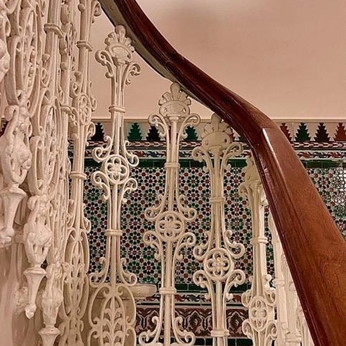 una escalera de hierro forjado con una barandilla de madera y una lámpara en el techo