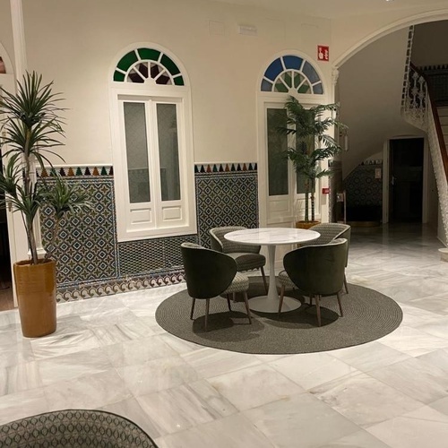 una sala de estar con una mesa y sillas y una planta