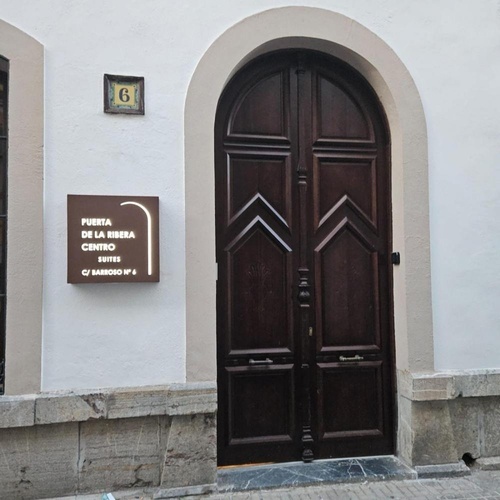 una puerta de madera con un letrero que dice puerta de la ribera centro de suites