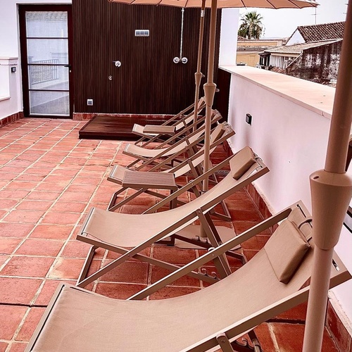 algunas tumbonas y sombrillas en una terraza con una puerta de madera que dice ducha