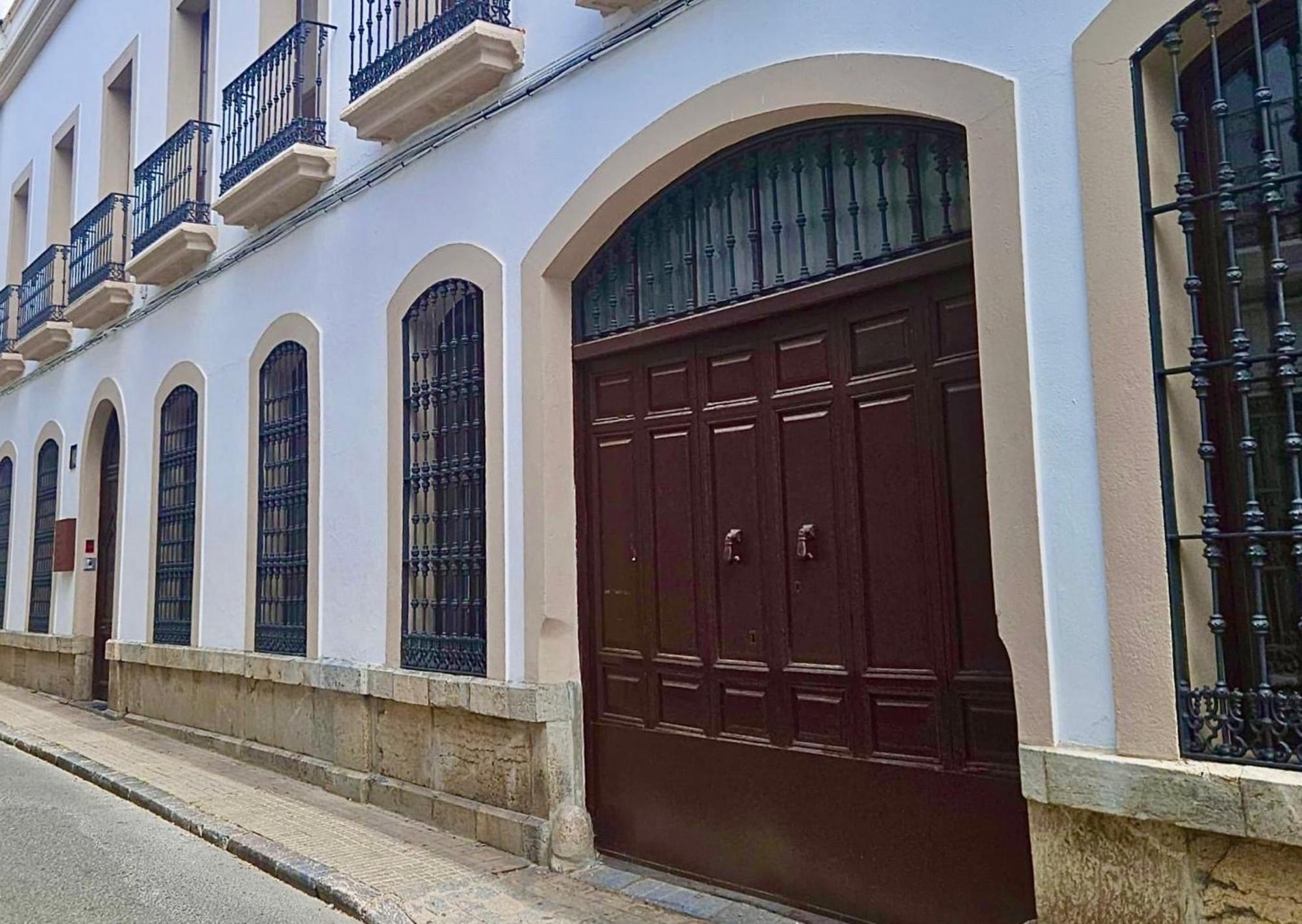 un edificio blanco con balcones y una puerta de madera