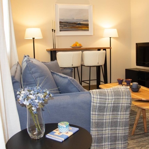 a living room with a blue couch and a painting on the wall