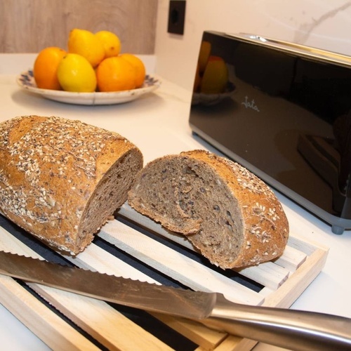 un trozo de pan está sobre una tabla de cortar de madera junto a una tostadora jata