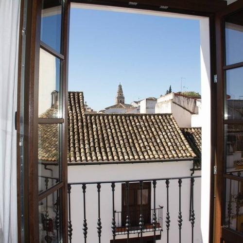 una ventana abierta que muestra un edificio blanco con techos de tejas