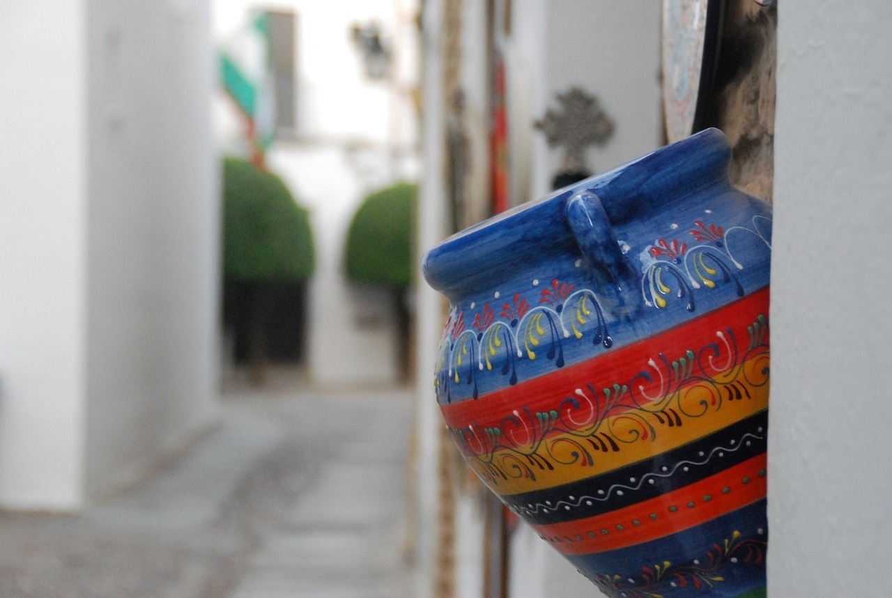 un jarrón colorido está colgando de una pared blanca