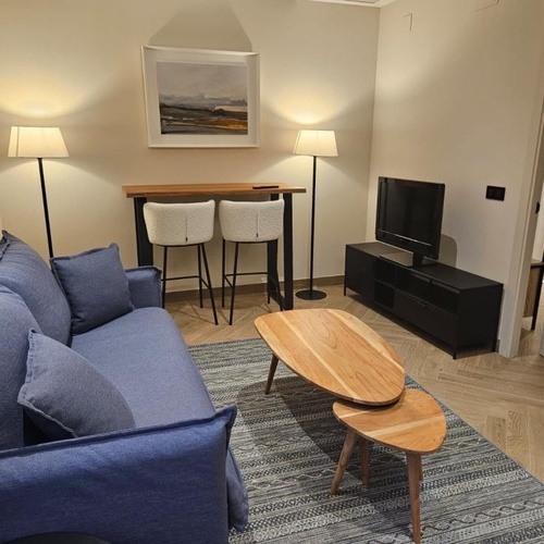 a living room with a blue couch and two wooden tables