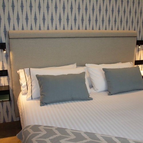 a bed in a hotel room with blue and white striped wallpaper