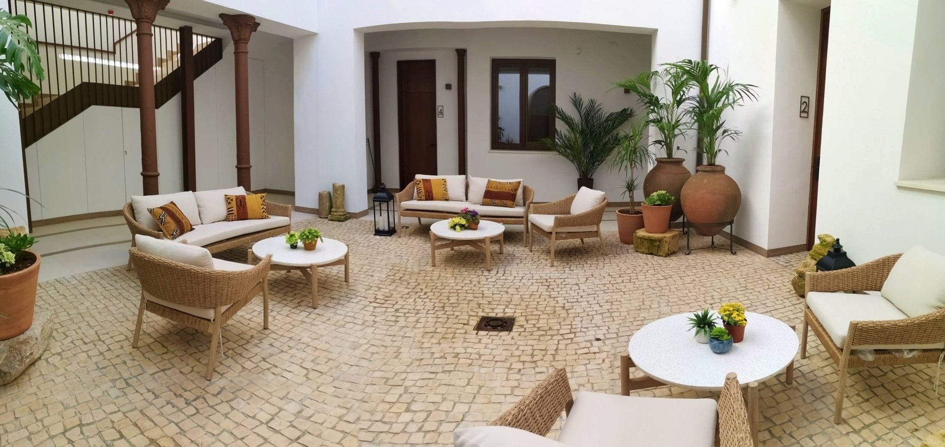 a courtyard with wicker furniture and potted plants