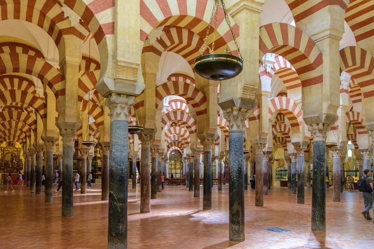 una habitación llena de columnas y arcos a rayas rojas y blancas