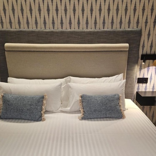 a bed with white sheets and blue pillows in a hotel room