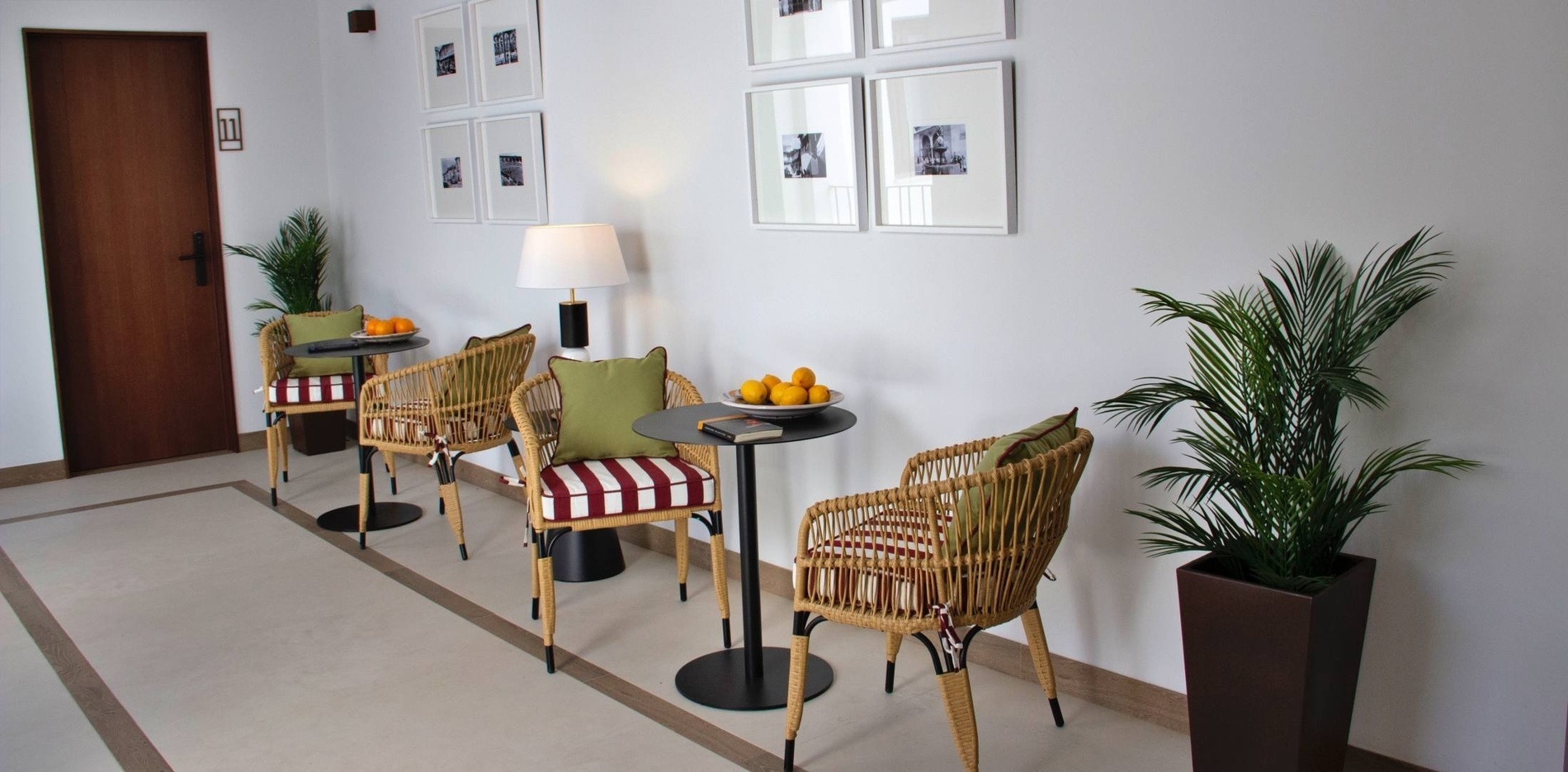 a hallway with wicker chairs and a table with a bowl of oranges on it