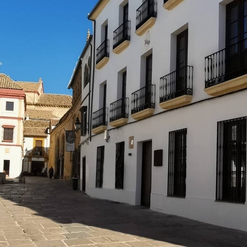 un edificio blanco con balcones negros está al lado de un edificio marrón