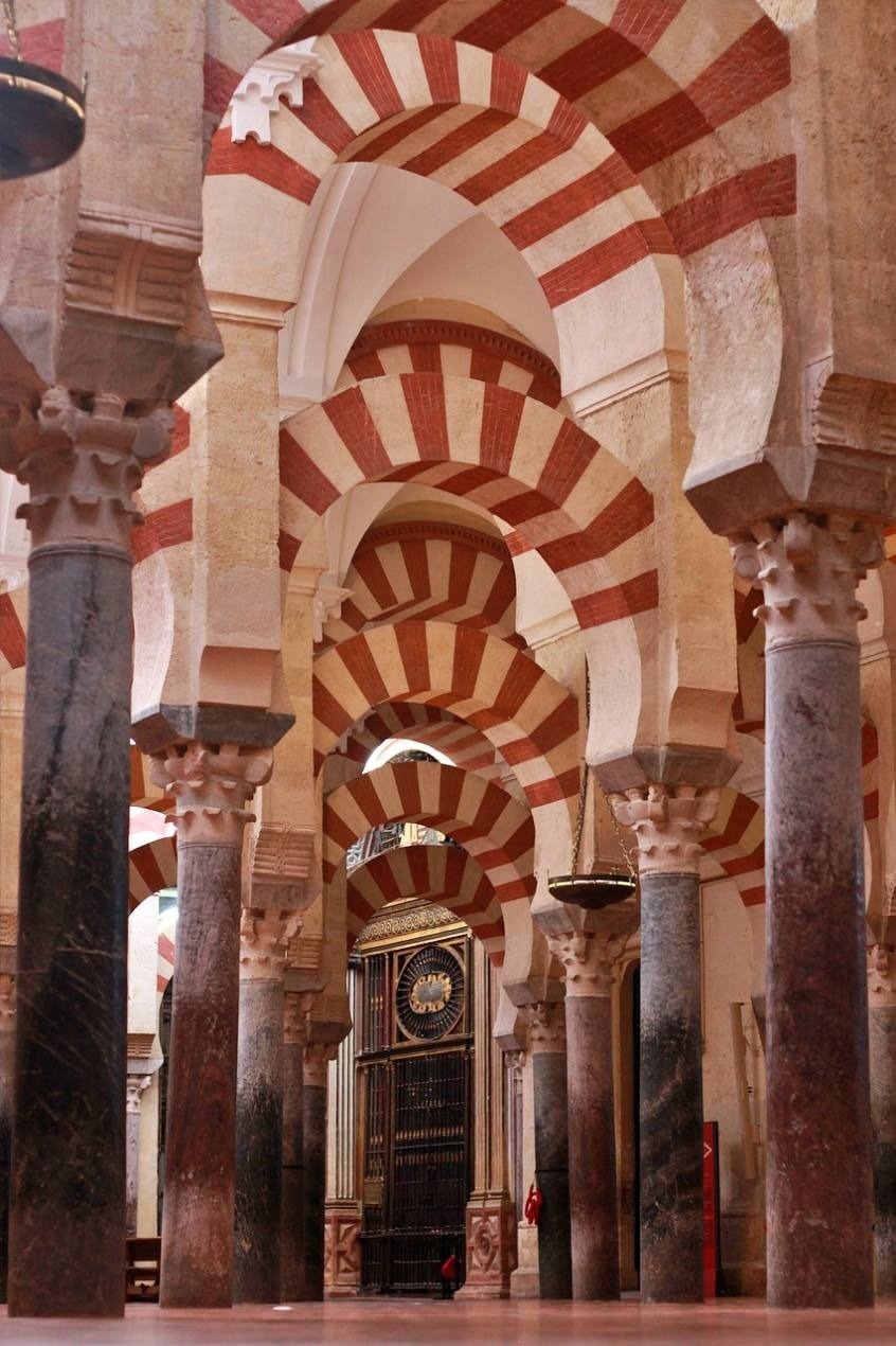 the inside of a building with arches and columns and a clock on the wall