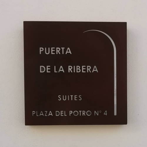 una placa marrón que dice puerta de la ribera suites plaza del potro no 4