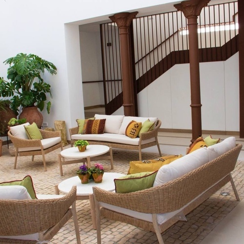 a living room with wicker furniture and a staircase in the background