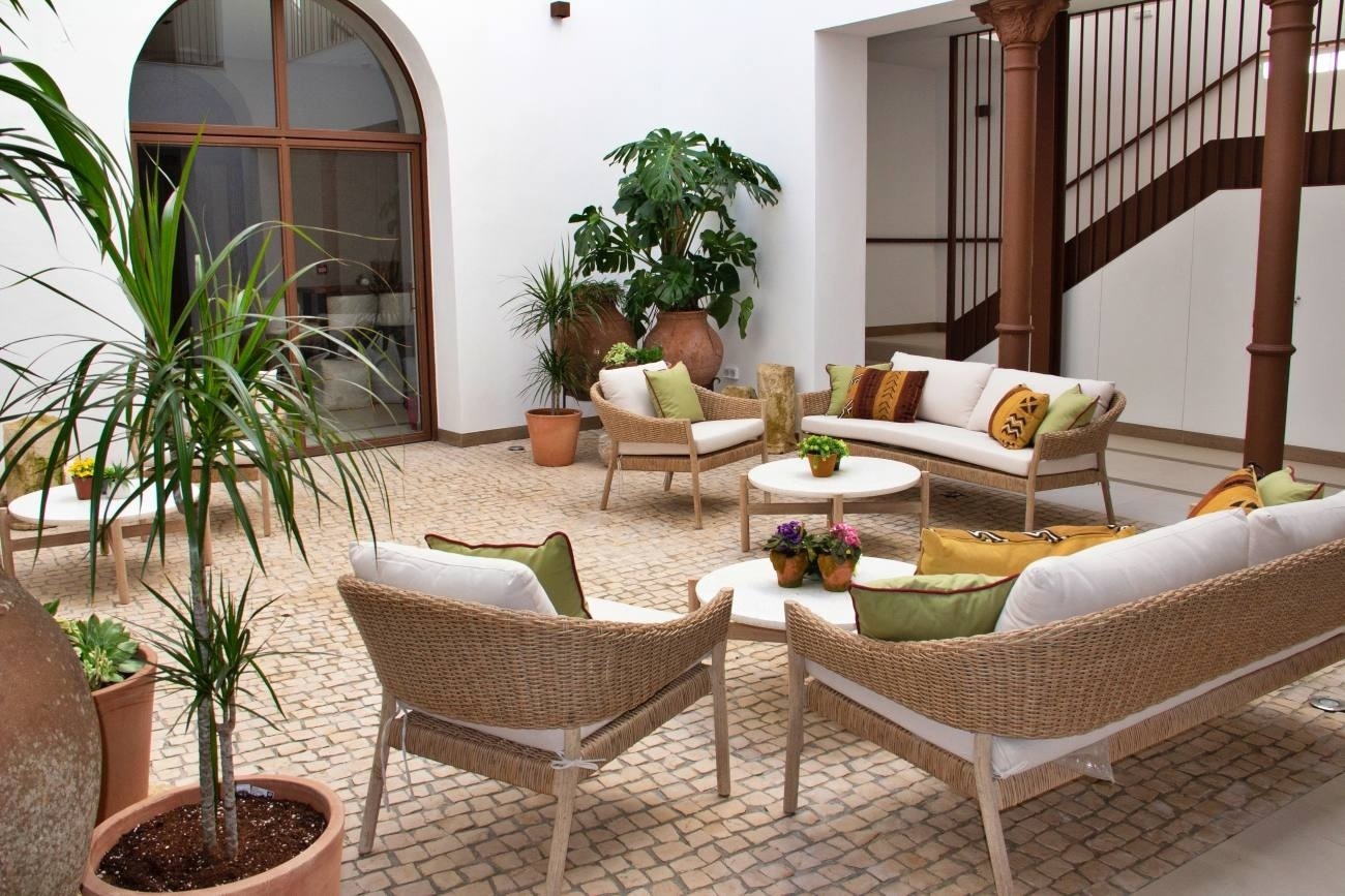 a courtyard with wicker furniture and potted plants