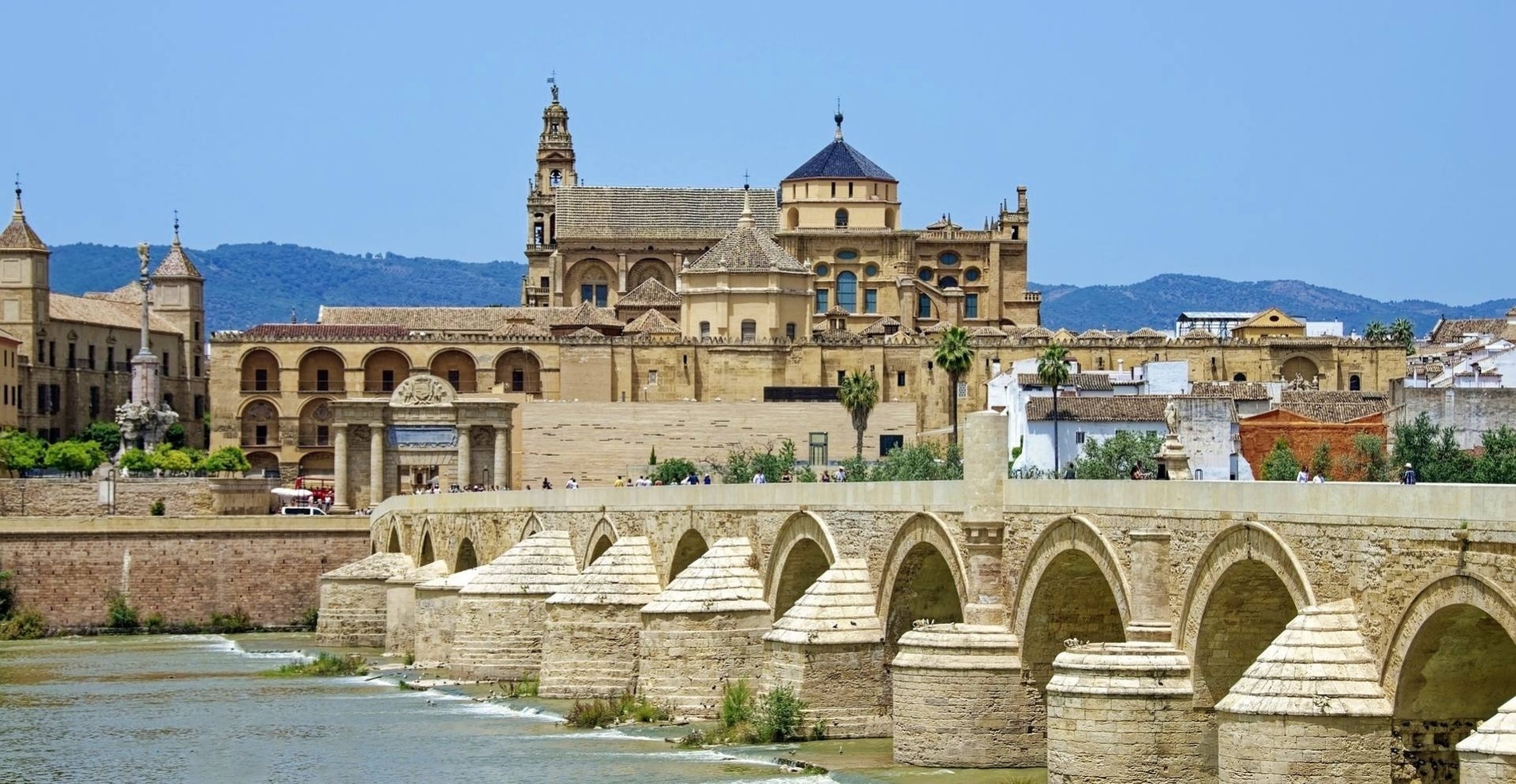 a bridge over a river with a large building in the background