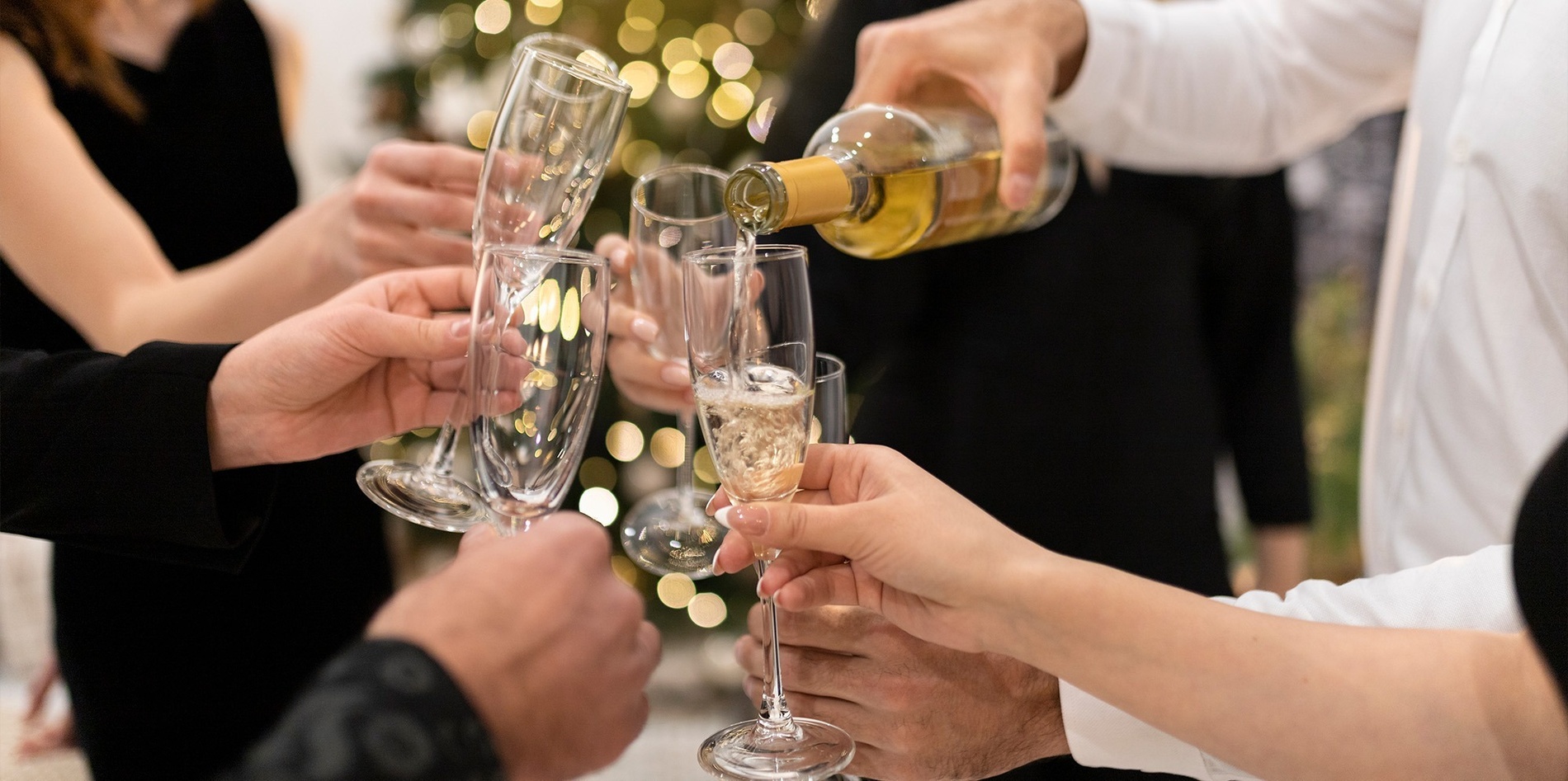 a group of people toasting with champagne in front of a christmas tree