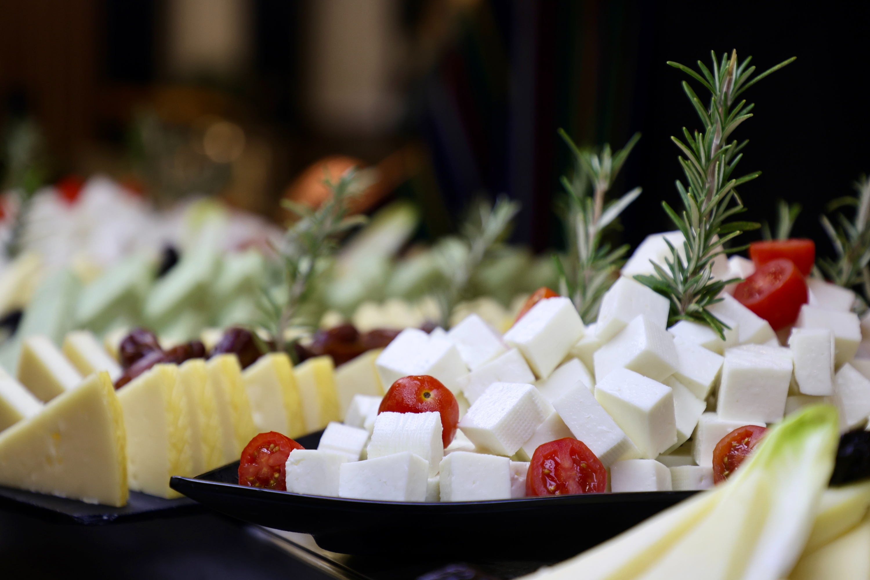 a tray of cheese cubes with tomatoes and rosemary on top