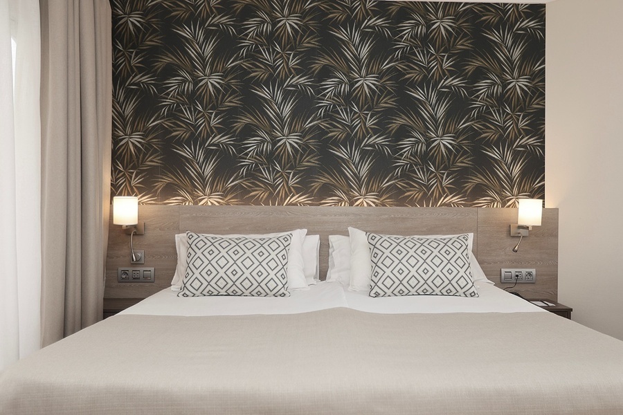 una habitación con una cama y una pared con un patrón de hojas