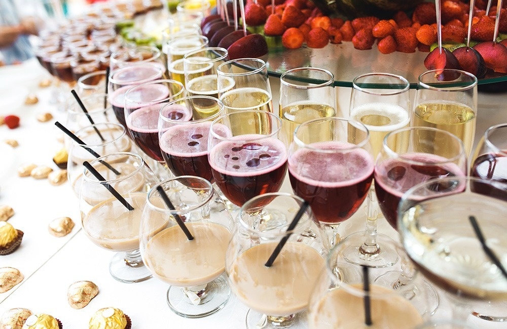 una mesa llena de copas de champán y bebidas con pajitas