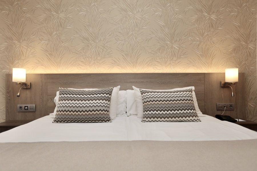 una cama con dos almohadas y dos lámparas en la pared