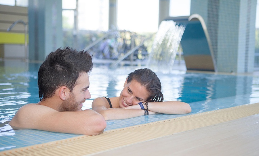 a man and a woman are leaning on the edge of a swimming pool