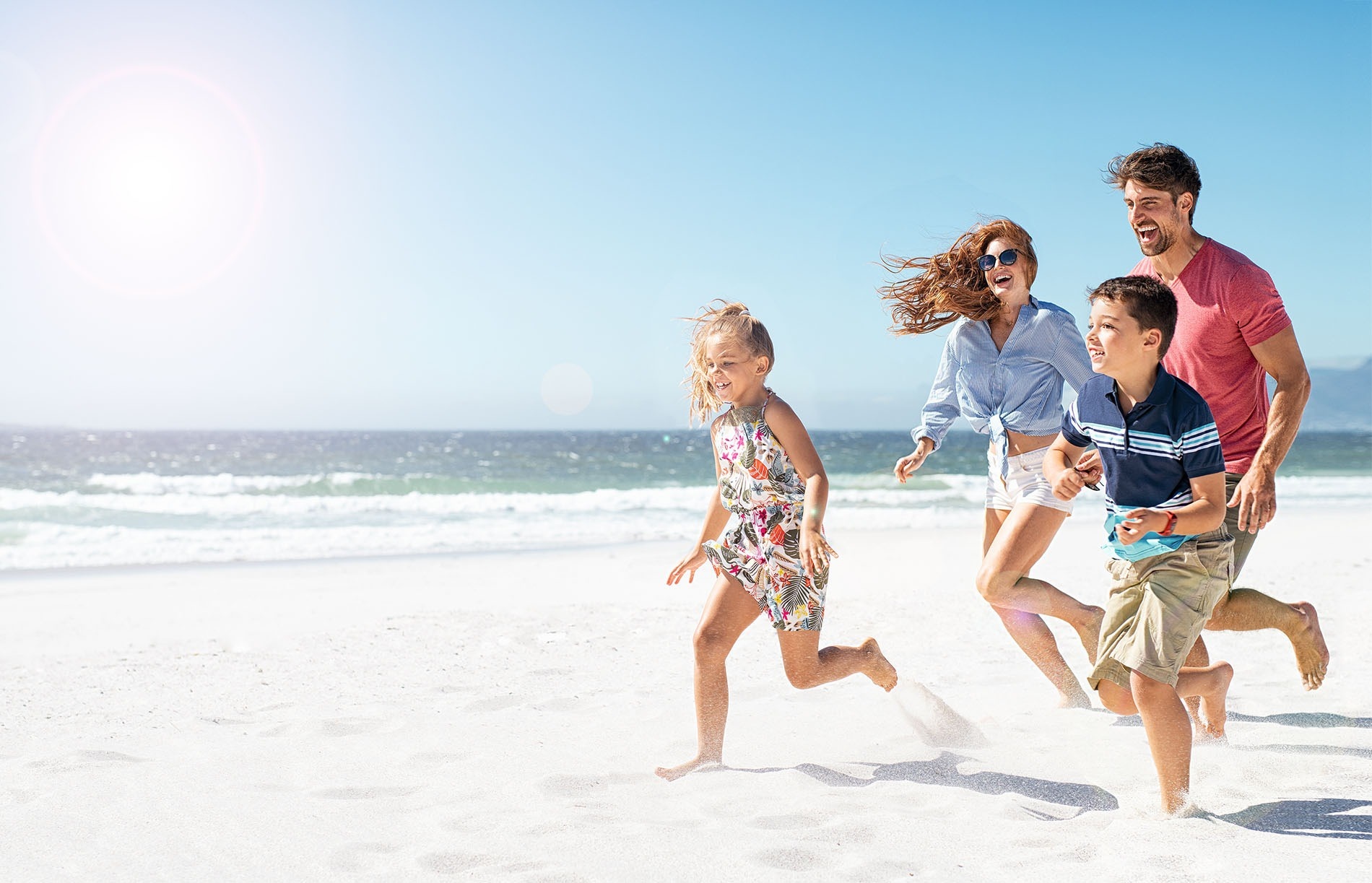 una familia corre por la playa en un día soleado