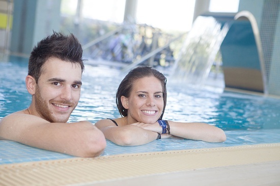 a man and a woman are leaning on the edge of a swimming pool