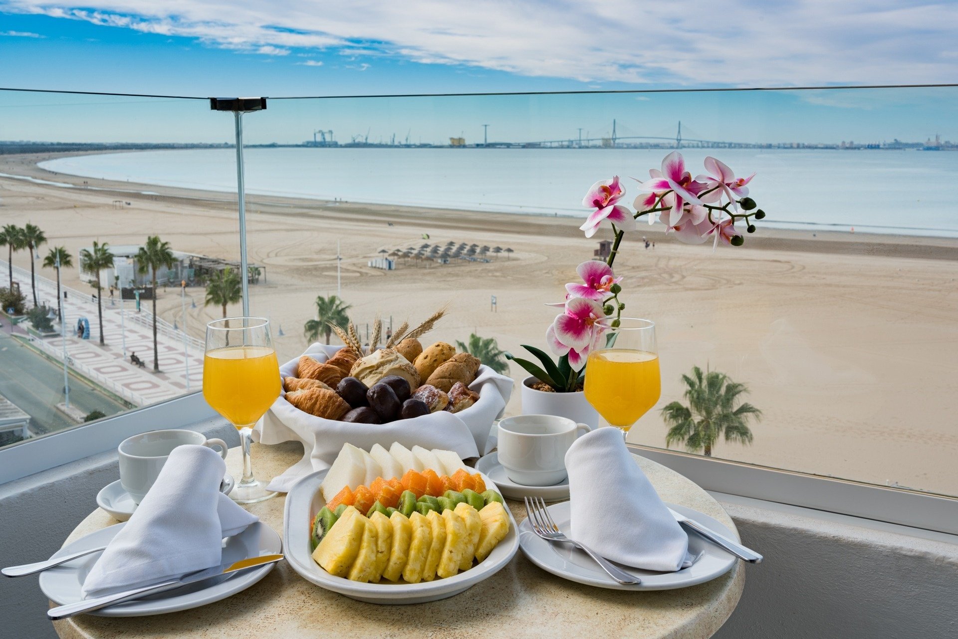 una mesa llena de comida y bebidas con una vista de la playa en el fondo