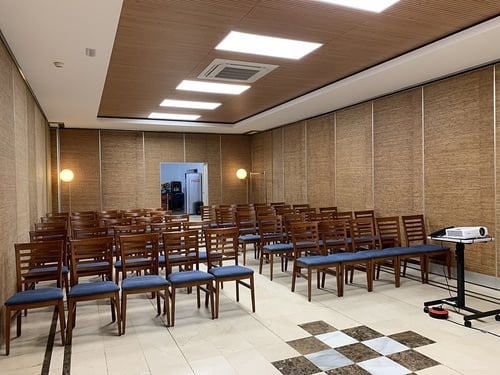 una habitación llena de sillas de madera y una pantalla