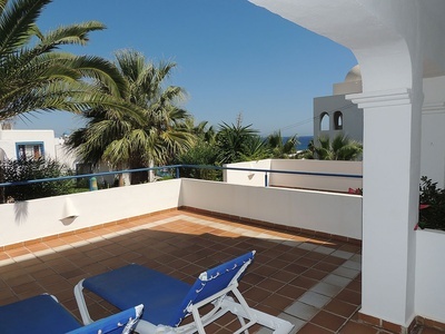 a balcony with blue lounge chairs and palm trees