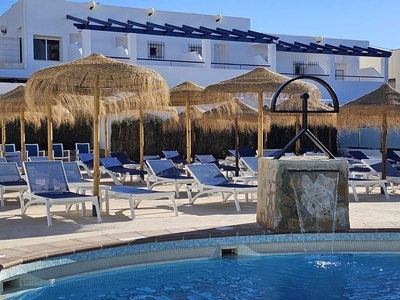 una piscina rodeada de sillas y sombrillas y una cascada - 