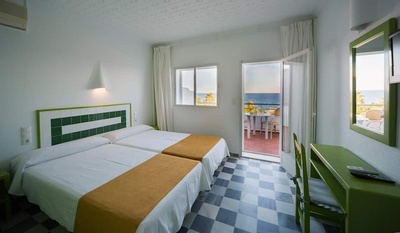 a hotel room with two beds and a balcony overlooking the ocean
