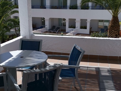 a white table with blue chairs on a balcony