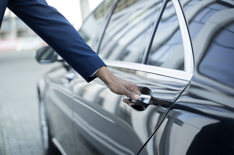 a man in a suit is opening the door of a car