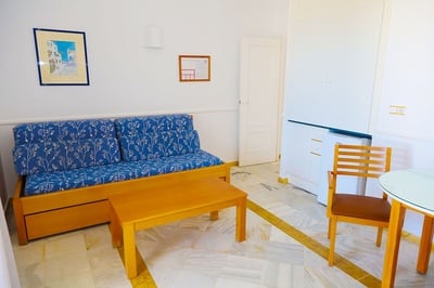 Salón acogedor en El Puntazo con sofá azul, mesa de madera y silla de comedor. - 